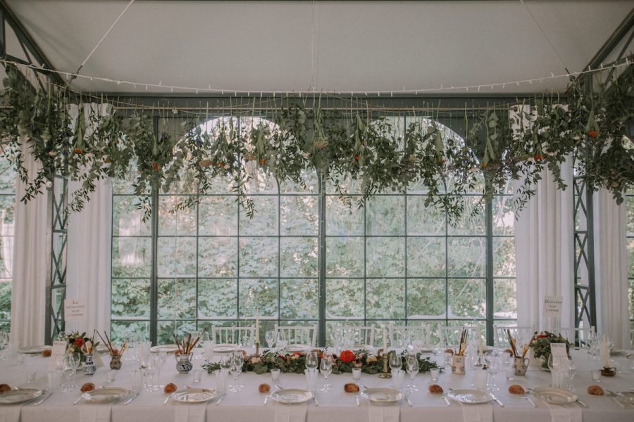 Une vue d'ensemble de la salle de réception, décorée de guirlandes de fleurs et de lumières scintillantes pour le mariage de Carole et Ali.