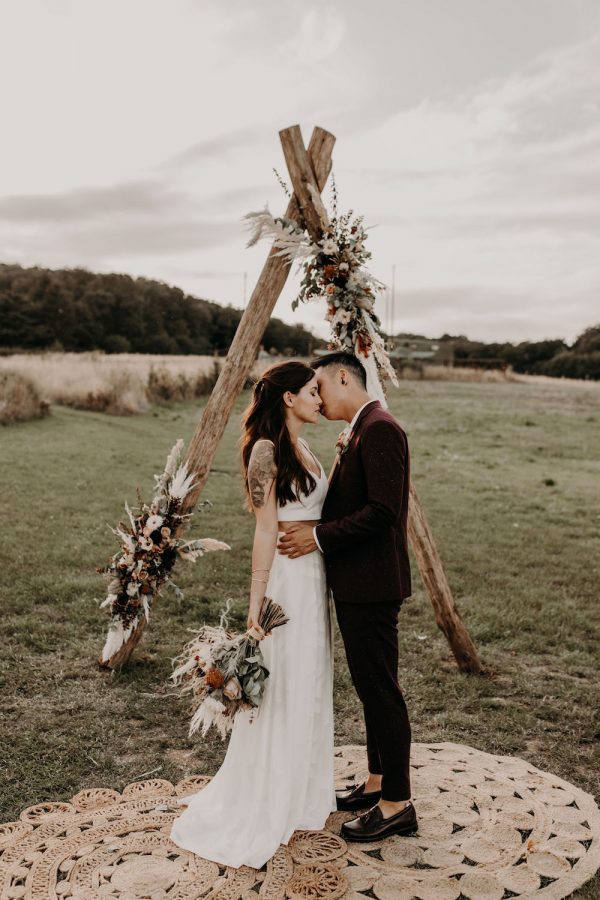 Un moment romantique entre Amandine et Nicolas sous une arche de fleurs colorées.